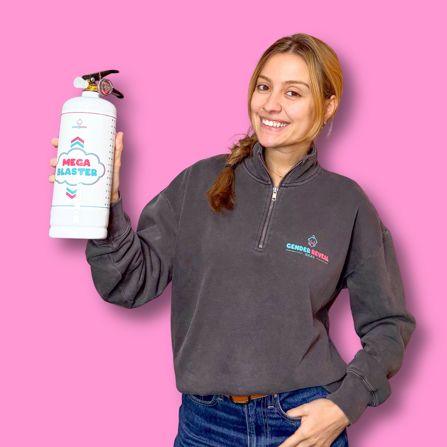 Woman holding a white Gender Reveal Extinguisher MEGA Powder Blaster against a pink background smiling