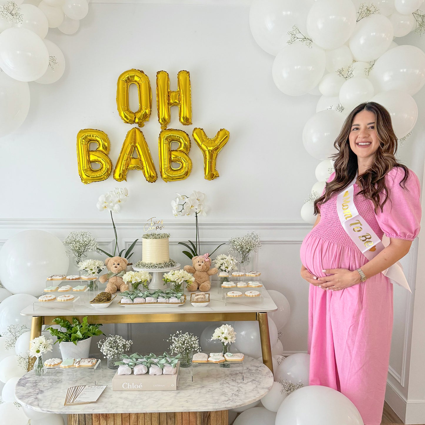 Baby Shower Party Box Set displayed at elegant dessert table with gold OH BABY balloon backdrop, white balloon arch, and marble table featuring teddy bears, treats, and baby's breath flowers. Styled with neutral decor for a sophisticated celebration setup.
