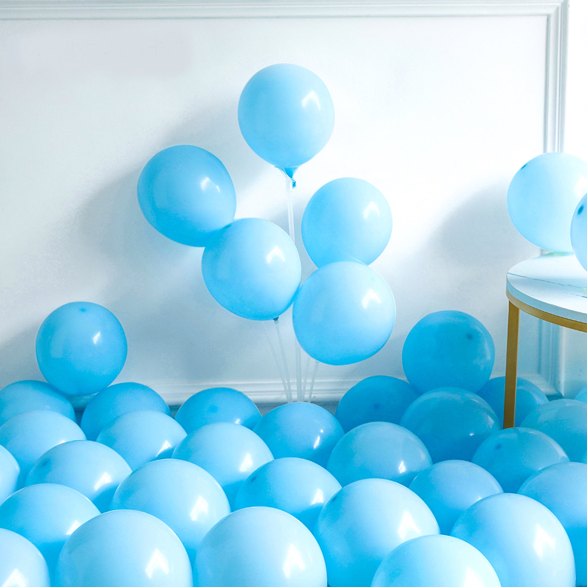 148 Piece Universal Gender Reveal Baby Shower Luxury Balloon Kit displayed with light blue and white balloons arranged in an elegant cascade against a white wall, creating a stunning backdrop for celebrations. Some balloons float while others form a beautiful base arrangement.