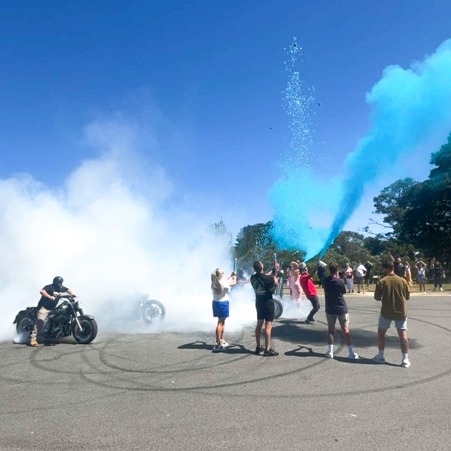 Mega Powder Blaster gender reveal creates dramatic blue cloud burst as crowd celebrates outdoors with motorcycle burnout display