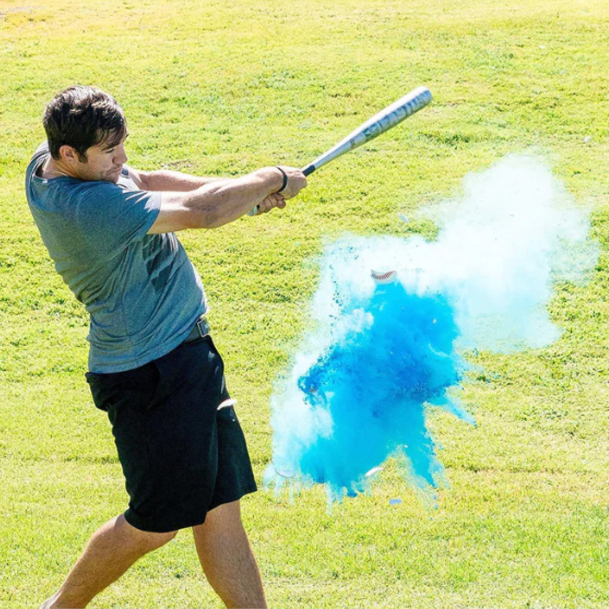 Sports Gender Reveal Baseball captured mid-swing as batter hits powder-filled ball creating vibrant blue explosion against sunny green field background, showcasing exciting moment of gender announcement with baseball-themed celebration