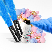 Mini blaster and two smoke bombs releasing vibrant blue powder with pink and gold balloon arch for gender reveal party