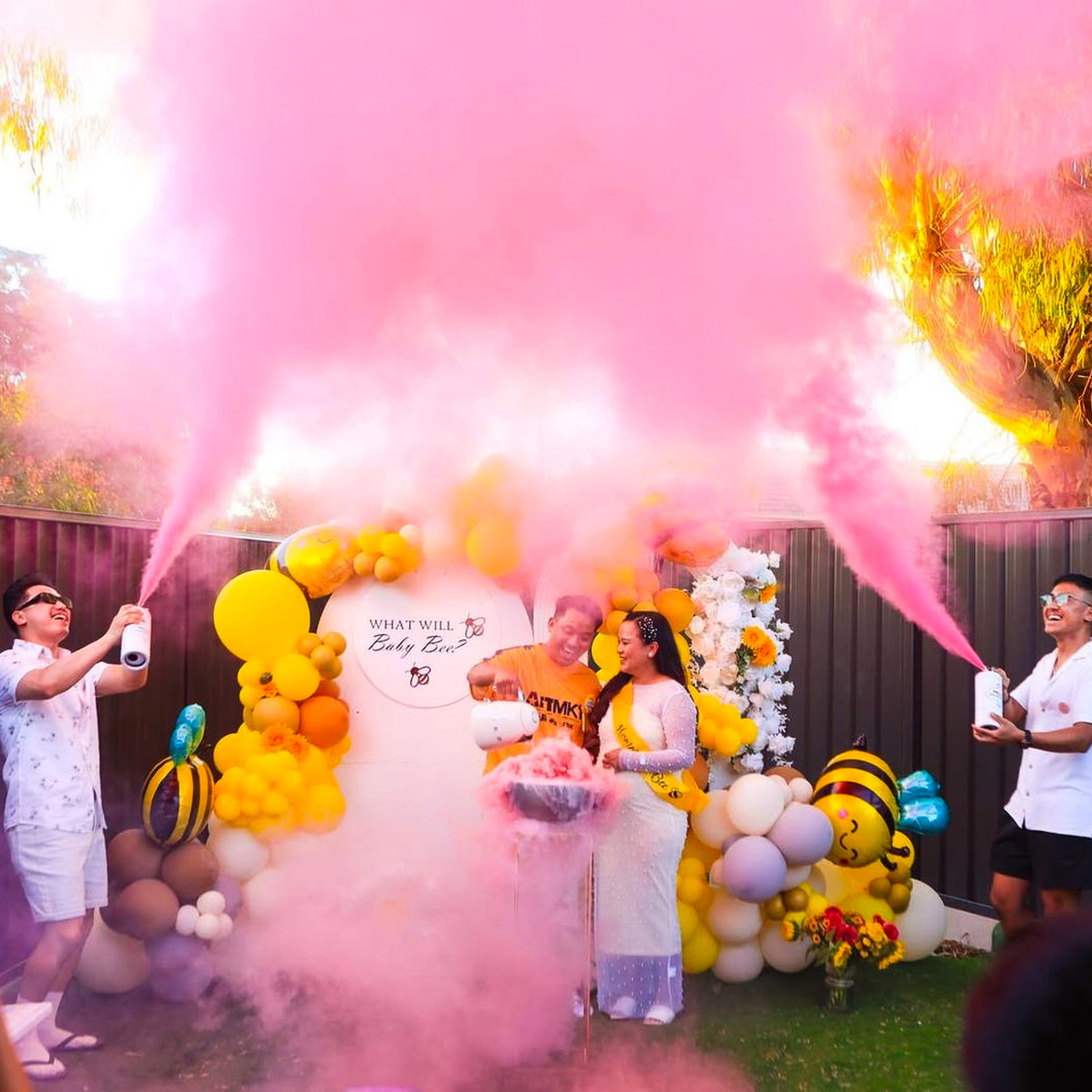 Gender Reveal Double MEGA Powder Blaster creating vibrant pink smoke explosion with balloon arch and decorative backdrop